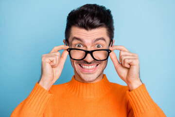 Photo of young excited man happy positive smile surprised news hands touch glasses isolated over blue color background