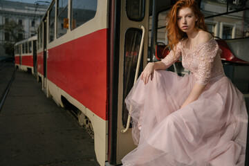 Eastern Europe public transport.  red-haired ginger young amazing beautiful girl sits on steps of...