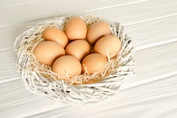 Fresh raw farm brown organic chiken eggs in the nest on white background. Natural healthy food.
