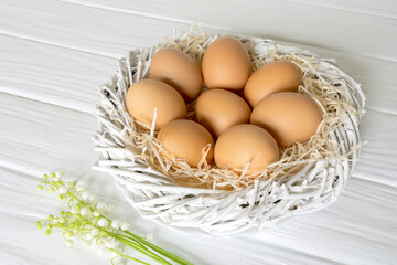 Fresh raw farm brown organic chiken eggs in the nest on white background. Natural healthy food.