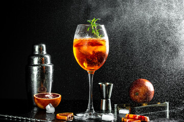 Aperol Spritz aperitif with oranges and ice with glass bloody oranges, red bitter, dry white wine, soda, zest and ice on black background