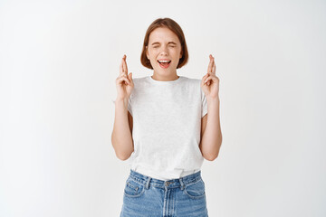 Excited hopeful woman close eyes, cross fingers for good luck, making wish with positive emotions,...