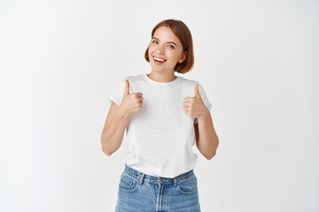Very good, nice work. Smiling girl say yes, showing thumbs up in approval, like and agree, making...