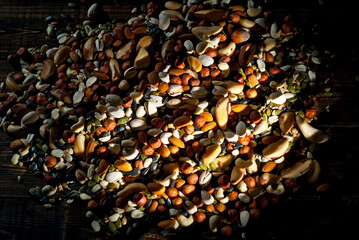 Many types of nuts close up. Textures of different nuts. Nuts are dumped in a pile. Contrasting dramatic light as an artistic effect.