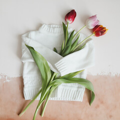 Overhead view of white knitted sweater and bouquet of fresh tulips