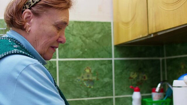 Close up and side view of seniour woman busy with hosehold chores. Retirement at home.