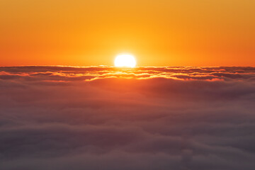 Fototapeta na wymiar Sol emergiendo sobre mar de nubes, cielo totalmente naranja
