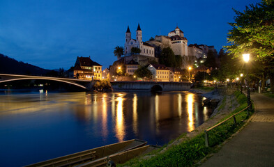 Fototapeta na wymiar night view of town with river, bridge and church on the rock / Aarburg, Switzerland