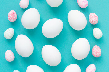 A pattern of white chicken eggs and small colored eggs on a blue background. Creative easter design