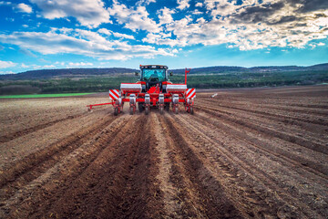 Fototapeta premium Farmer with tractor seeding crops at field