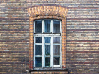 Old large window with wooden frame in brick building.