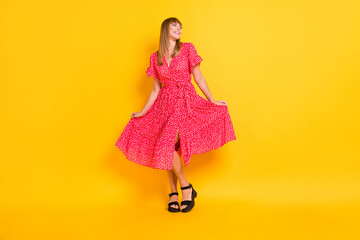 Full length photo of funny cute young woman dressed red outfit dancing holding dress isolated yellow color background