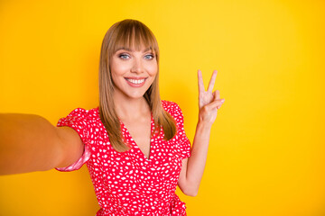 Photo of sweet shiny young lady wear red clothes tacking selfie showing v-sign isolated yellow color background