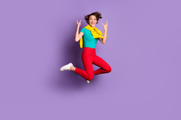 Full length photo of girl jump raise horns sign wear tied pullover t-shirt pants footwear isolated violet color background