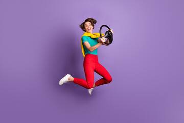 Full length photo of girl jump run hold steering wheel wear t-shirt pants footwear isolated violet...