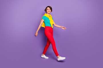 Fototapeta na wymiar Full length photo of girl walk wear knotted pullover t-shirt pants footwear isolated violet color background