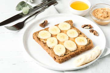 Homemade peanut butter sandwich with bananas and honey on wooden background.