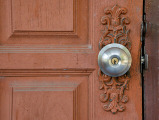Silver metal door knob on wooden door.