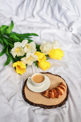 Obraz na płótnie Canvas Breakfast in bed. A bouquet of tulips lies on the bed next to a cup of hot coffee. Spring. Gift. Good morning.