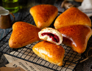 homemade tasty triangle baked sweet buns, piroshki or mini pies with berries filling on wicker metal tray 