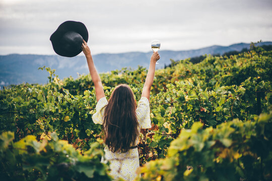  Woman relaxing in the vineyards. Woman holding glass with white wine.