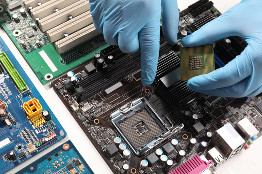 Technician repairing computer motherboard at table, closeup. Electronic device