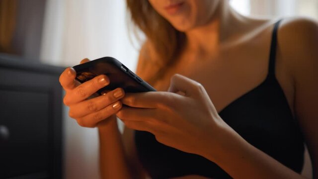Close view: Female hands texting using mobile phone or cellphone in hotel room against window
