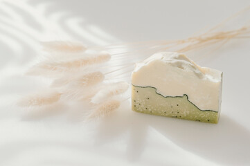 Handmade soap and dried bunny tail grass. Sunshade shadow on white background. Zero waste, eco friendly cosmetics concept. Vintage color filter.