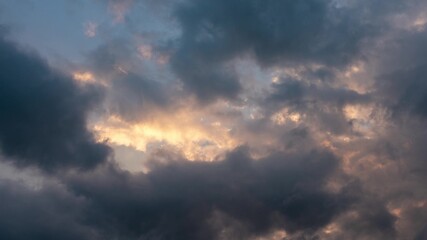 CLOUDS SHOWS THE IMPACT OF GLOBAL CLIMATE WARMING. Abstract clouds backgrounds. Dark dramatic clouds move fast. Ragged thunderclouds cover the sunny areas of the sunset sky