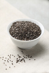 Bowl with chia seeds on light grey table