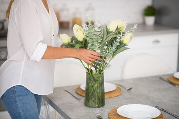 Woman decorating the kitchen with white beautiful flowers