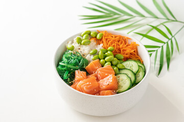 Poké bowl with fresh salmon, rice, chukka salad, edamame beans, carrots and cucumber. Bowl of healthy food on white background 