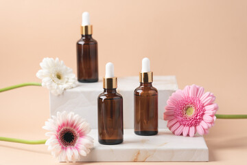 Cosmetic bottles with dark glass pipette on podium of marble boxes. Natural serum concept. Beige background