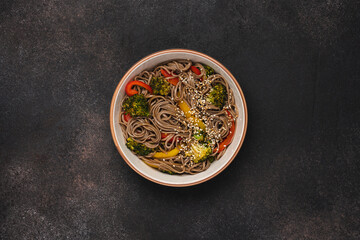 Fried buckwheat noodles with broccoli, colorful bell peppers and sesame seeds. Vegan stir fry in bowl. Healthy food 