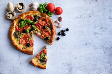  Vegetarian homemade pizza on a light background with a cut piece. Next ingredients -mushrooms, tomatoes, garlic, Basil, olives.   The concept of healthy eating.