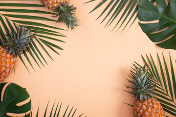 Top view of fresh pineapple with tropical leaves on pastel orange background.