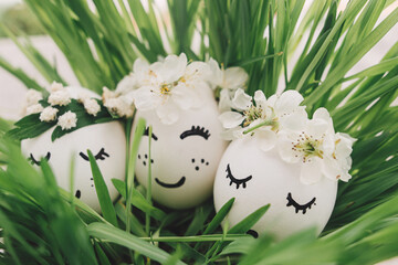 Easter eggs with drawn sleeping faces in floral wreaths in green grass. Happy Easter. Easter hunt