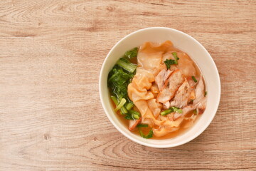 Chinese dumpling topping slice red barbrcue pork with clear soup on bowl