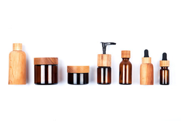 Top view of different sizes wooden and glass bottles containers blank mockup for skincare beauty cosmetic products for body or face isolated on white background. Zero waste and eco-conscious life.