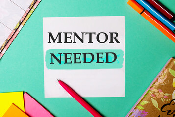 MENTOR NEEDED written on a turquoise background near bright stickers, notepads and markers