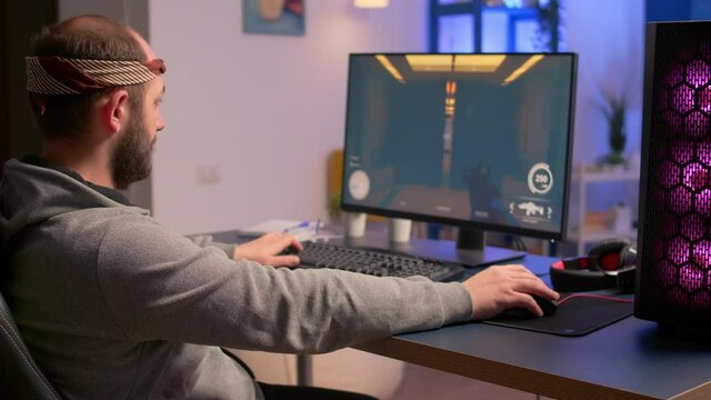 Caucasian man playing online video games for virtual championship using professional RGB system desktop. Pro gamer siiting on gaming chair looking and smiling at camera late at nigh in home studio.