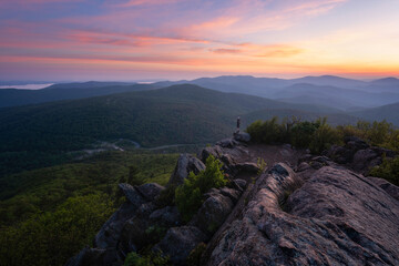 A hiker at the summit of Mary's Rock taking in a gorgeous Summer sunrise in Shenandoah National Park.