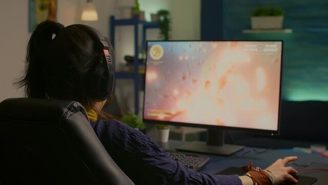 Concentrated gamer woman losing virtual multiplayer game on powerful computer at home with professional headphones. Digital gamer using RGB equipment for shooter space gaming competition late at night