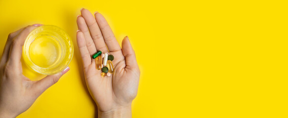 hands on yellow background, pills water cure virus. Selective focus
