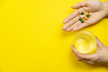 hands on yellow background, pills water cure virus. Selective focus