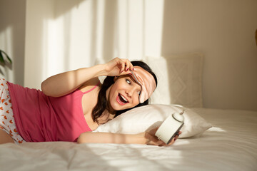 beautiful young woman waking up with an alarm clock 