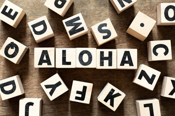 Wood letter block in word aloha on wood background with another alphabet