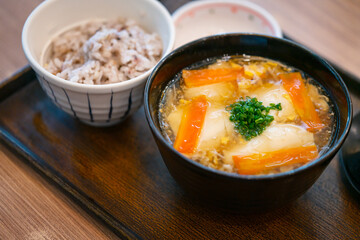 Close up Japanese vegan food, fresh soft tofu in egg soup and vegetables, mini rice bowl, food on wooden tray at table's resturant.
