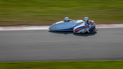 A panning shot of a racing sidecar as it corners on a track.