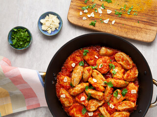 Poultry and dumplings stew in tomato sauce with garlic and coriander garnish. Romanian cuisine: Ostropel de Oltenia.